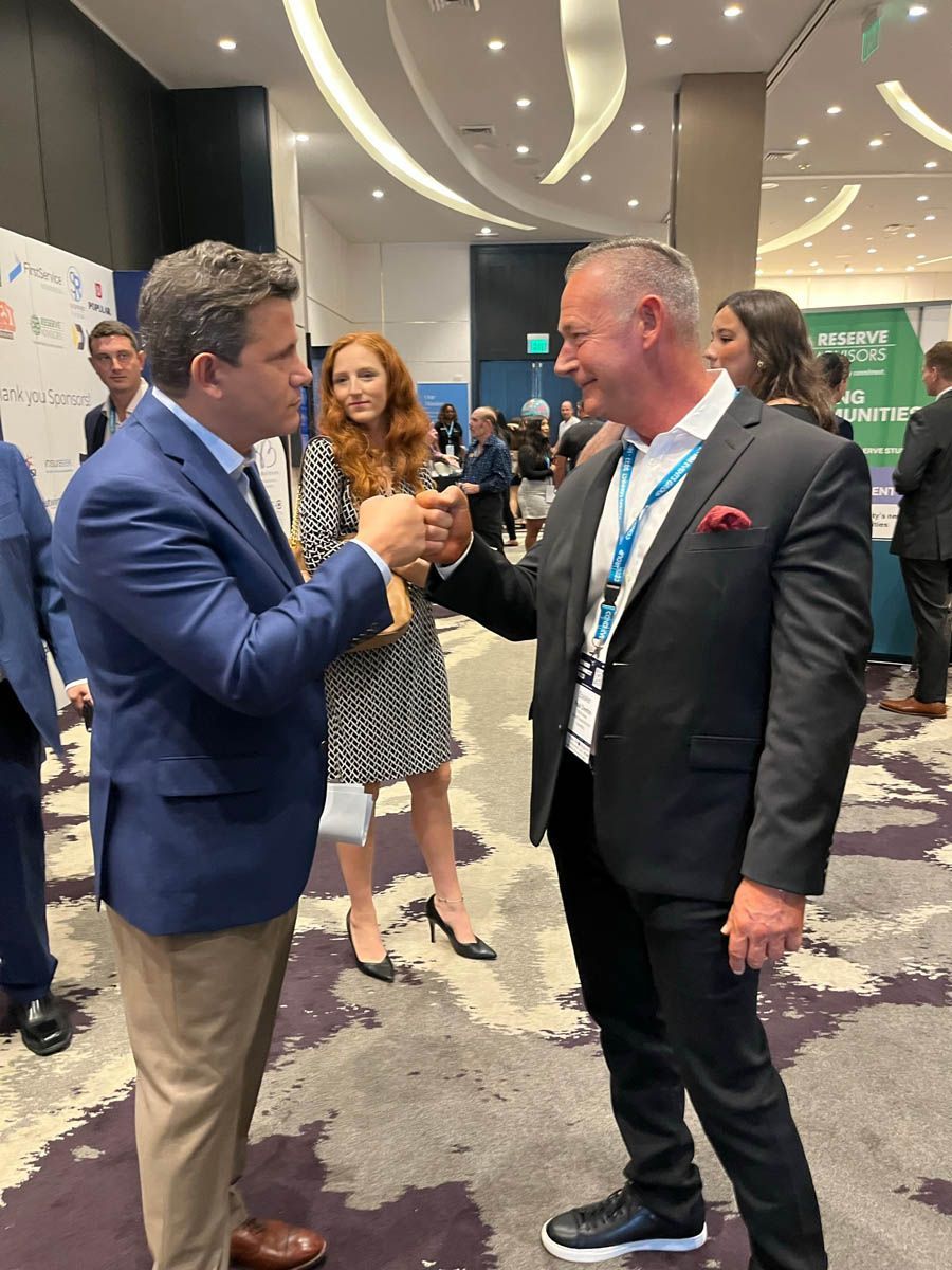 Two men in suits are talking to each other in a room.