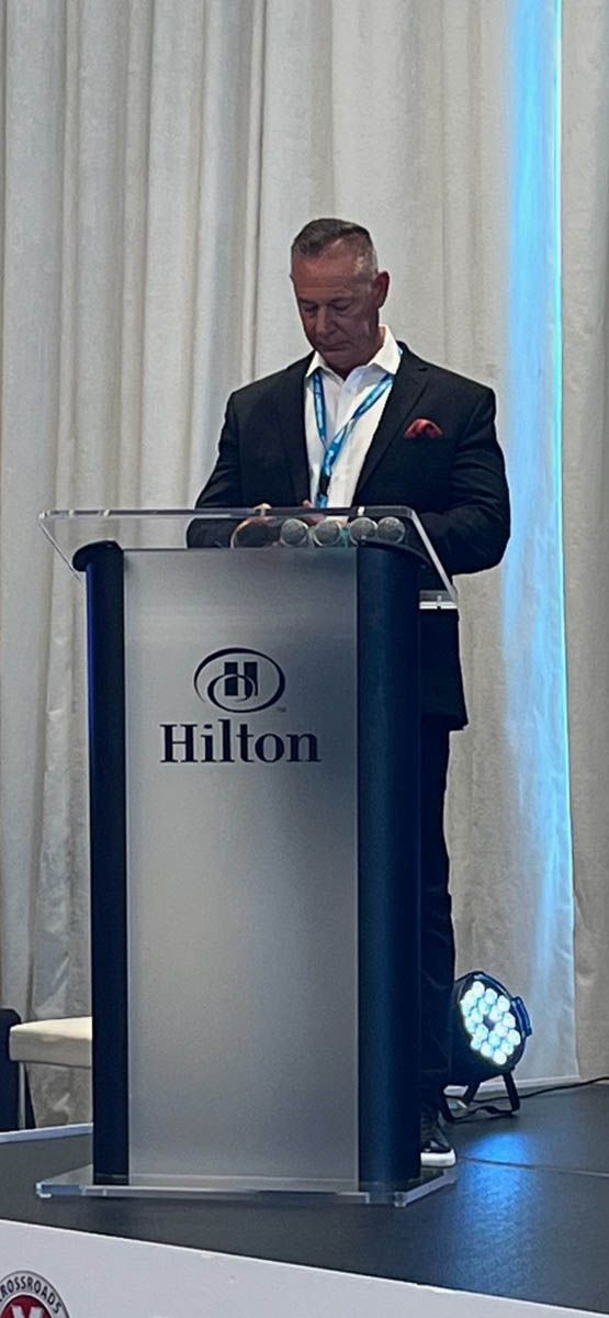 A man in a suit is standing at a podium giving a speech.