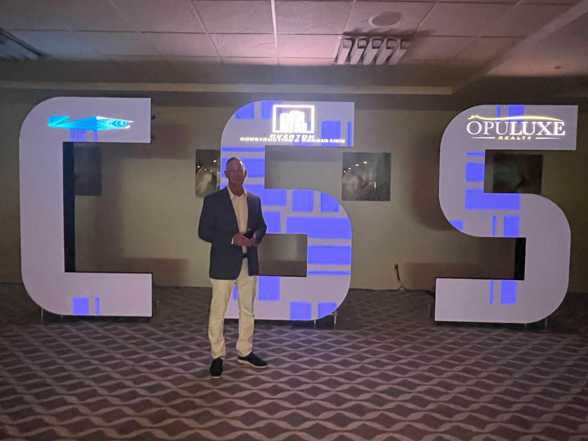 A man in a suit stands in front of a sign that says css