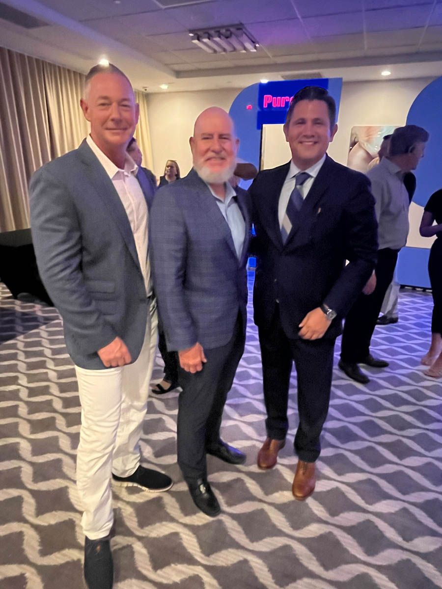 Three men in suits are posing for a picture in a room.