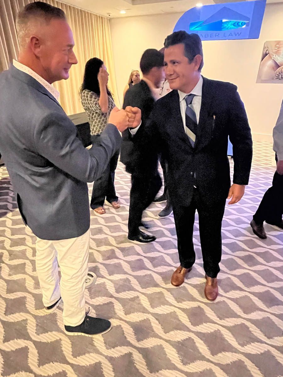 Two men in suits are shaking hands in a room.