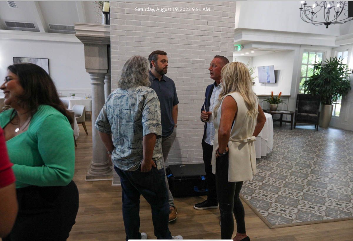 A group of people are standing in a room talking to each other.