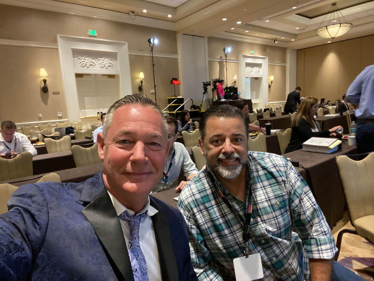 Two men are posing for a picture in a conference room.