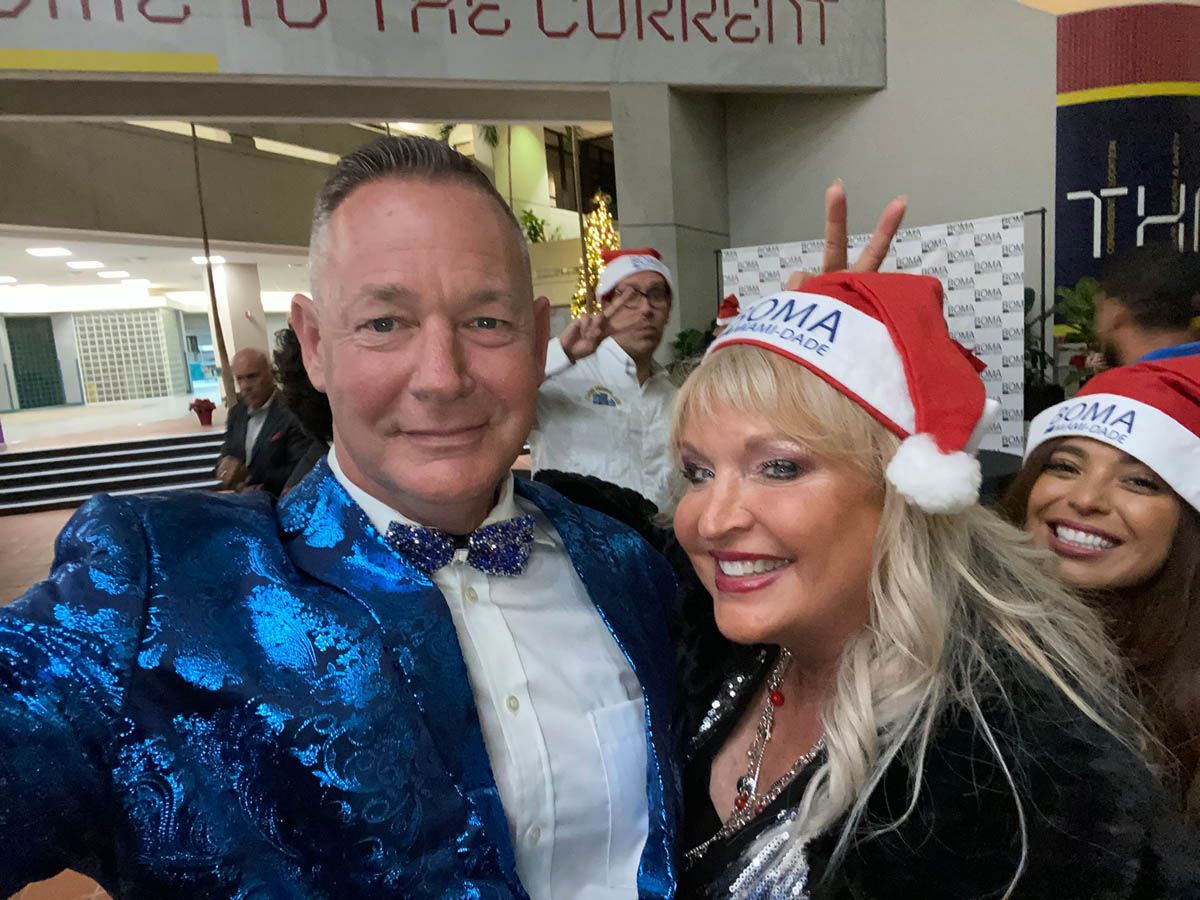 A man and woman wearing santa hats are posing for a picture