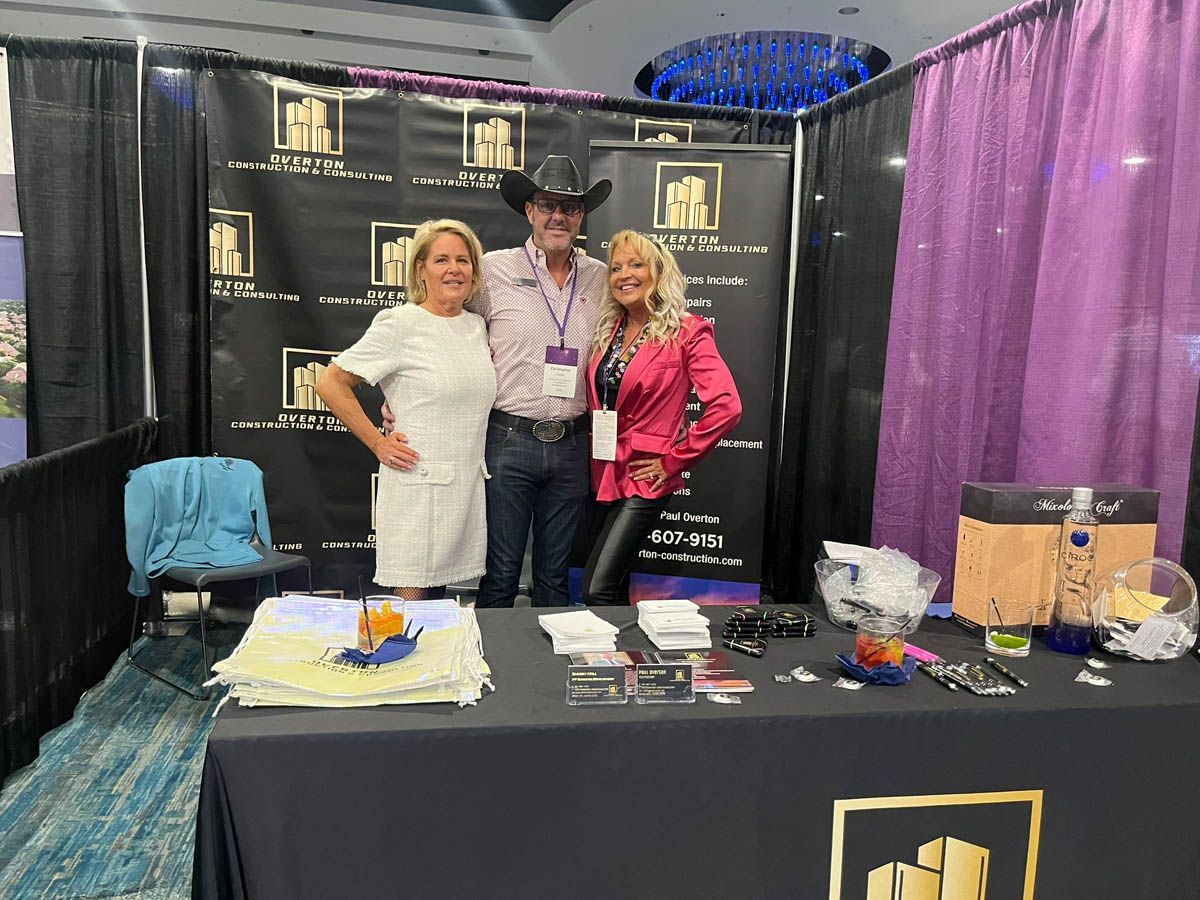 A group of people standing around a table at a convention.