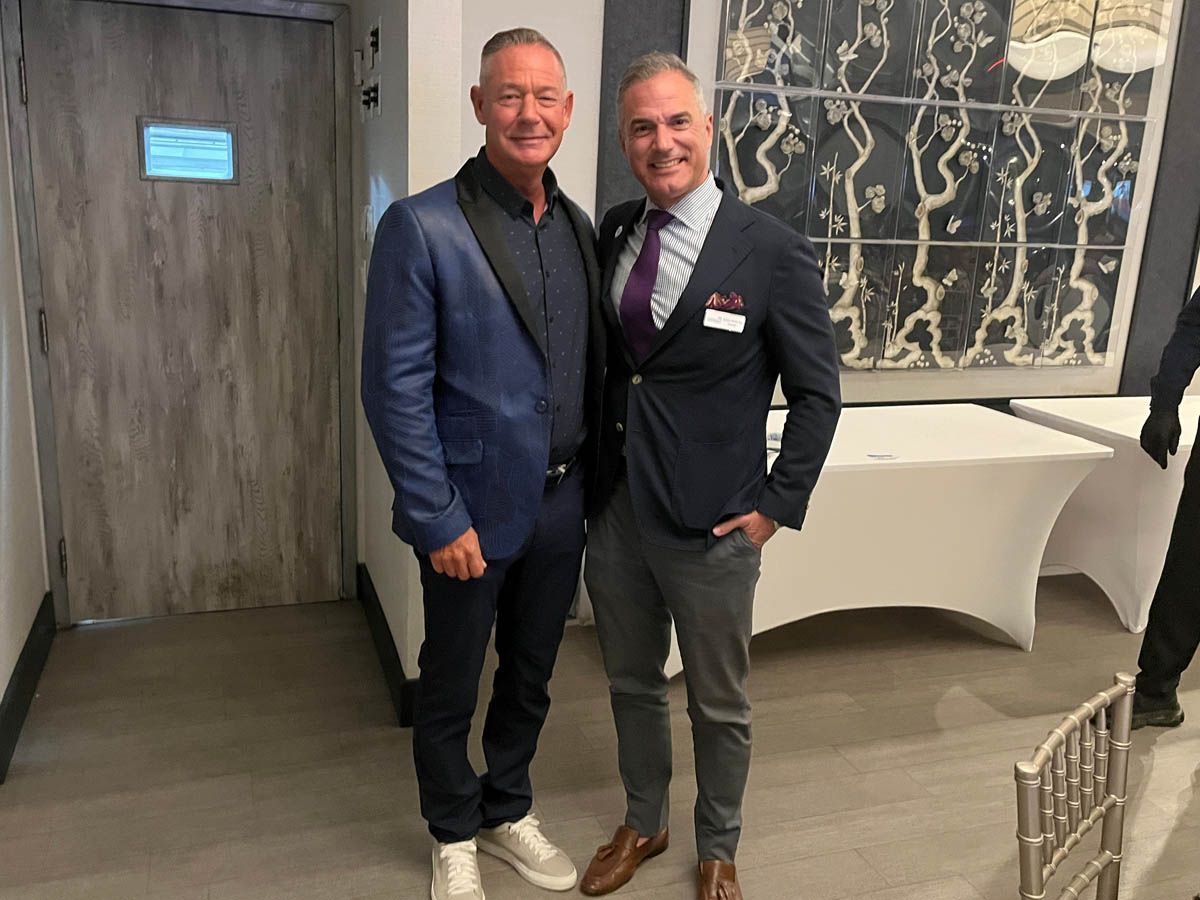 Two men in suits and ties are standing next to each other in a room.