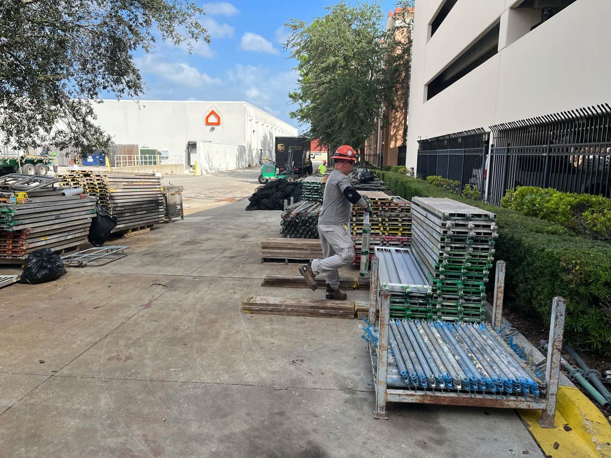 A man is carrying a pallet of scaffolding in a parking lot.