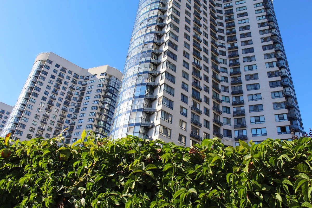 A tall building with a lot of windows is behind a hedge.
