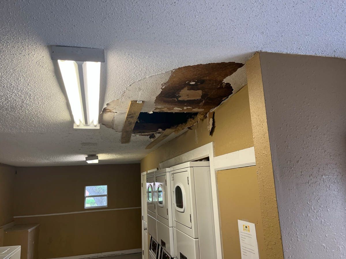 There is a hole in the ceiling in a laundry room.