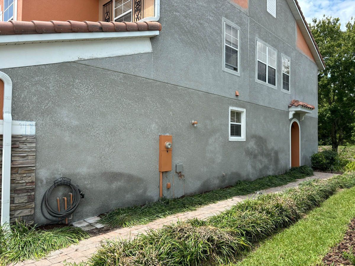A large gray and orange house with a walkway leading to it.