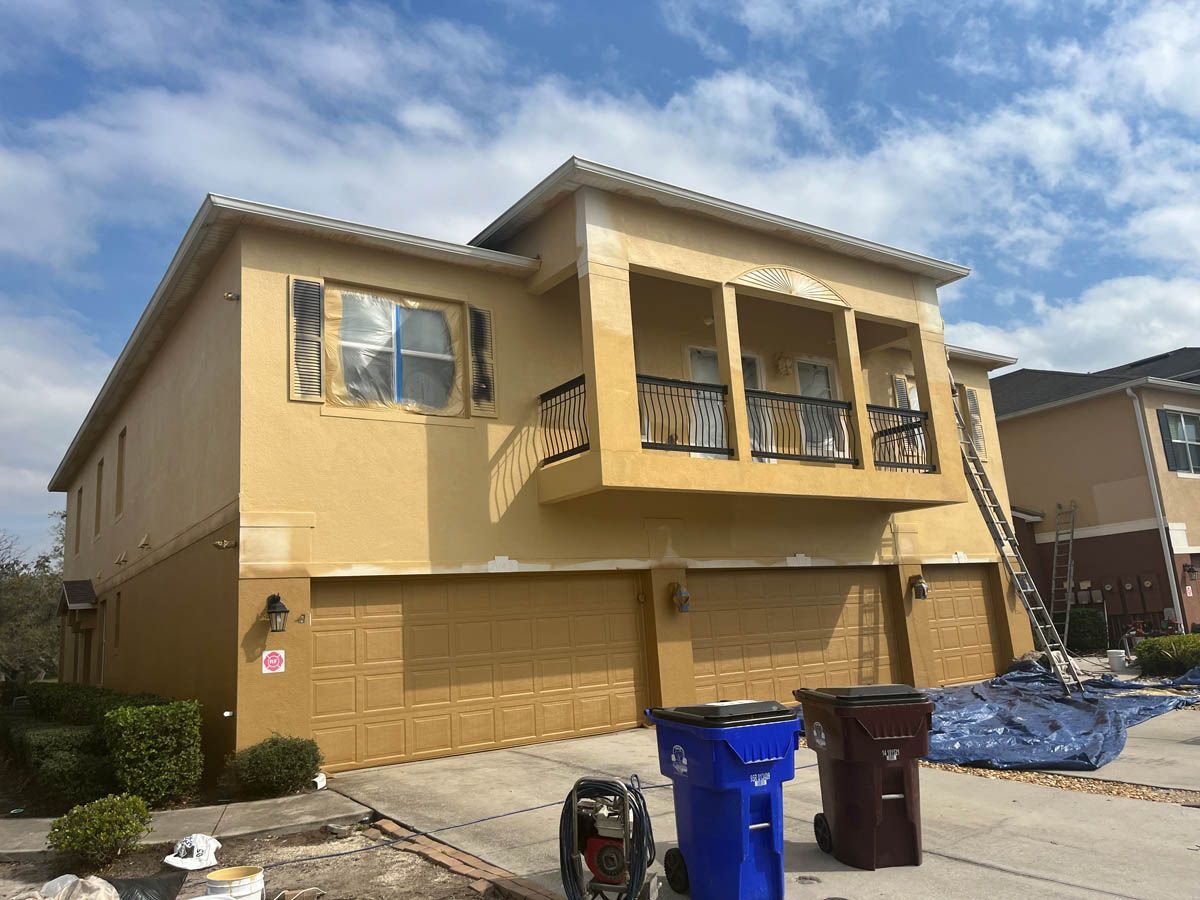 A large house with a balcony is being painted yellow.