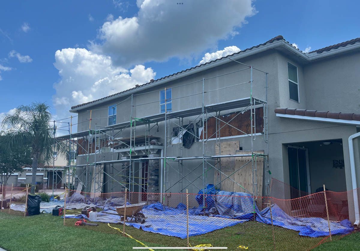 A large house is being painted with scaffolding in front of it.