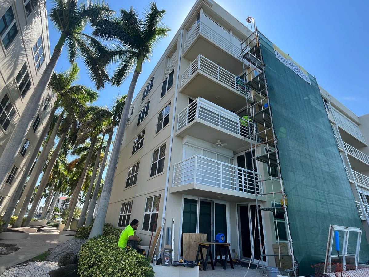A large building is being painted with a green scaffolding.