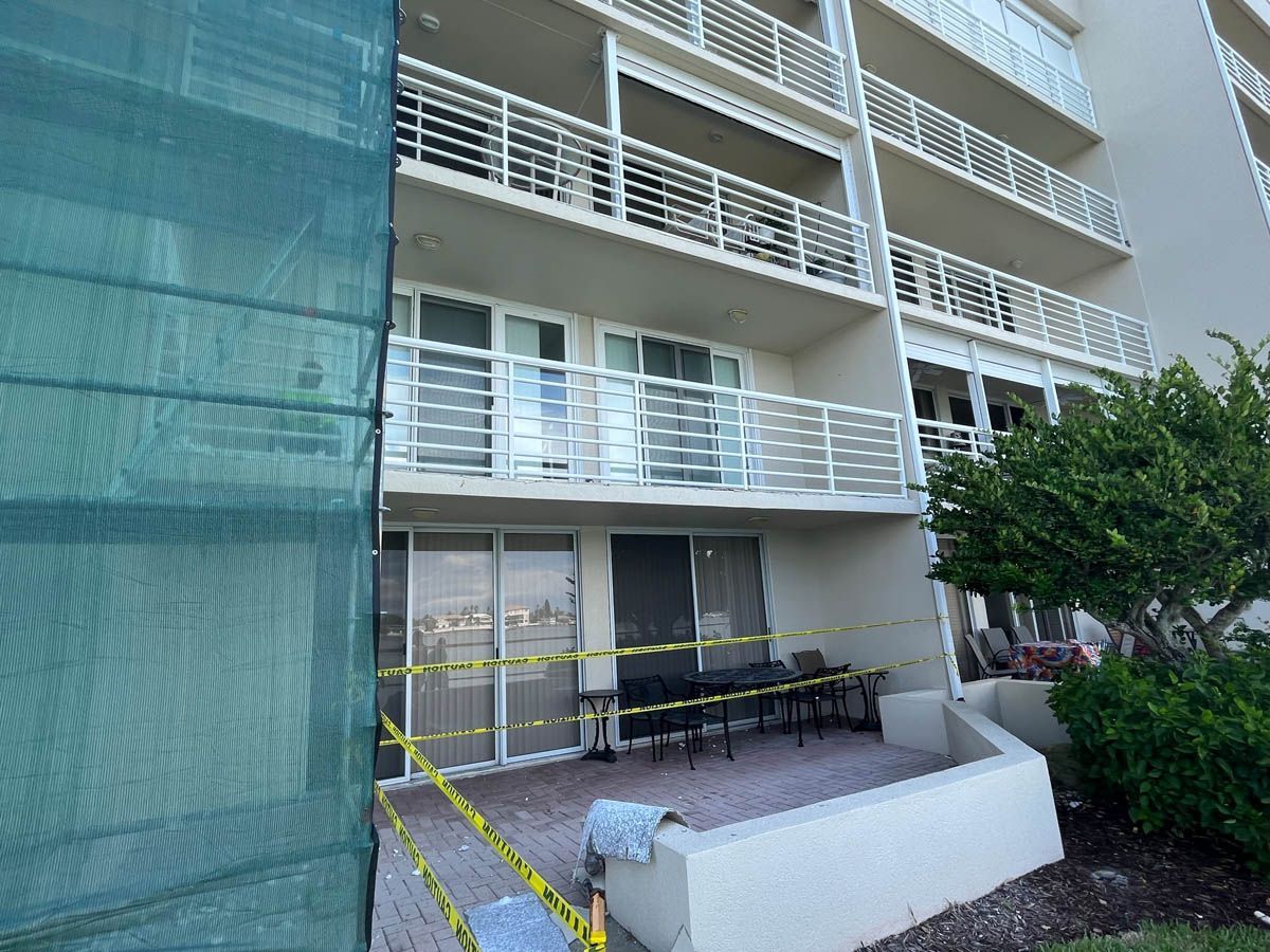 A building with a balcony and a green tarp covering it