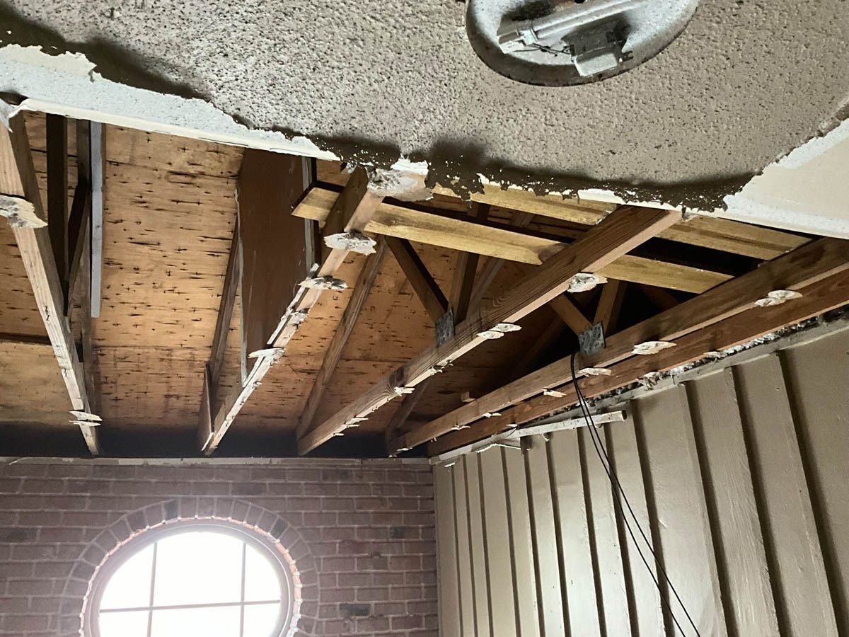 A room with a brick wall and a wooden ceiling with a round window.
