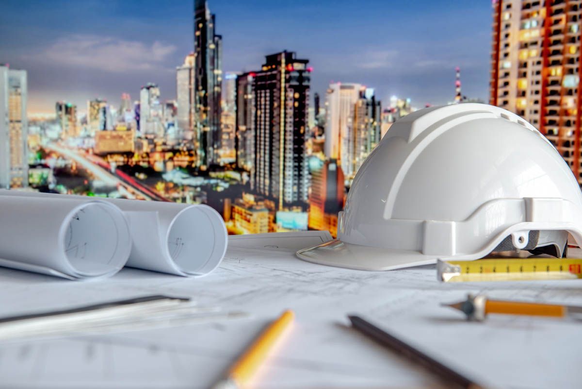 A hard hat is sitting on top of a table with a city in the background.