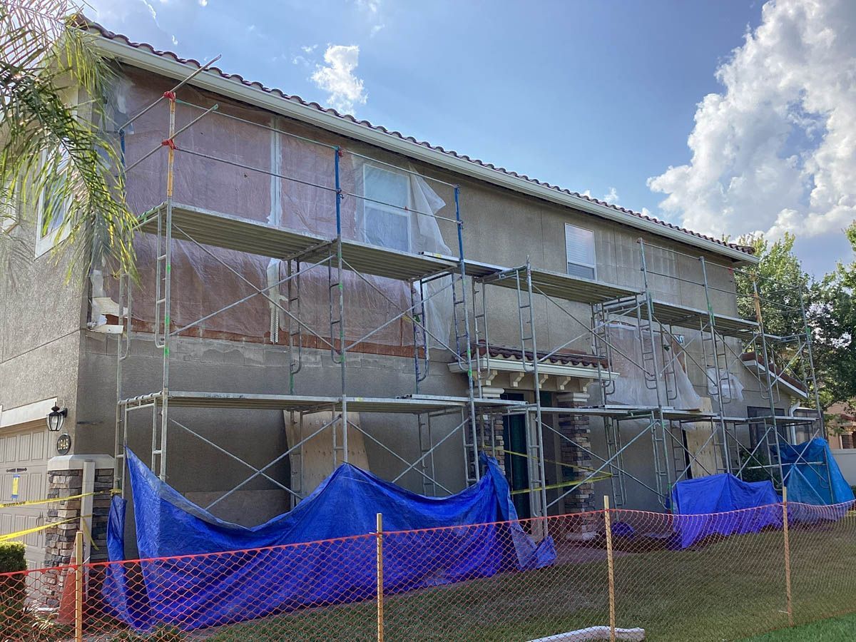 A building is being painted with scaffolding and a blue tarp.