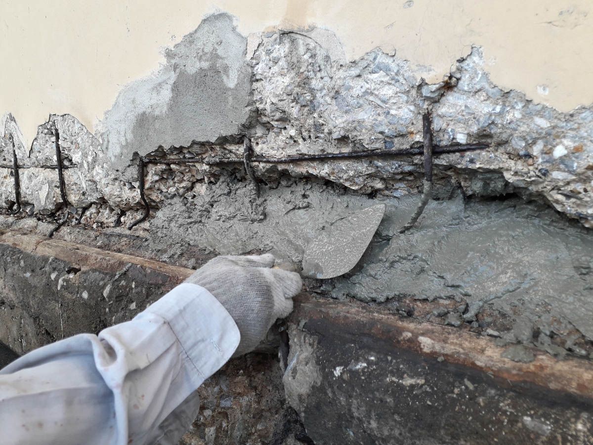 A person is using a trowel to spread cement on a wall.