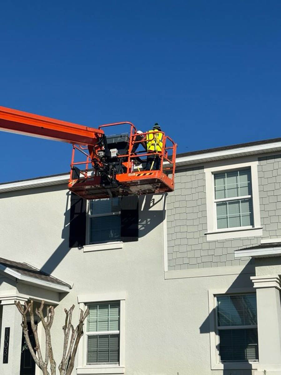 Two men are standing on a crane on top of a house.
