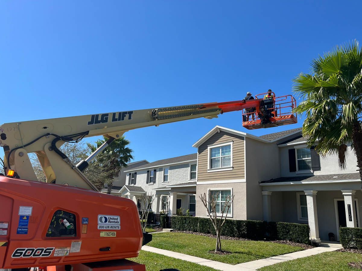 A jlg lift is being used to clean the roof of a house.