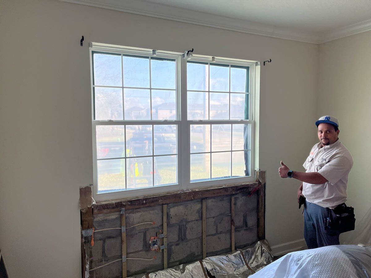 A man is standing in front of a window in a room.