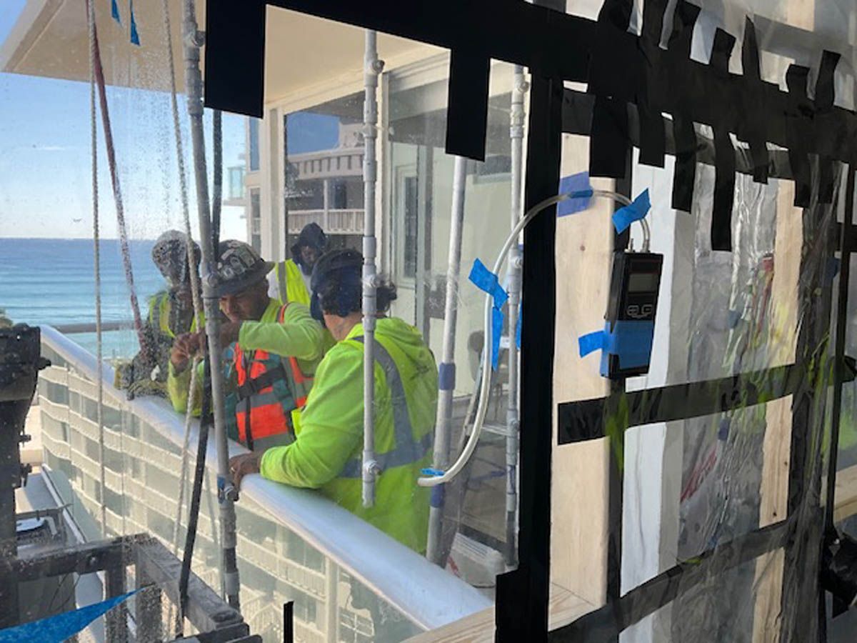 A group of people are working on a balcony overlooking the ocean.