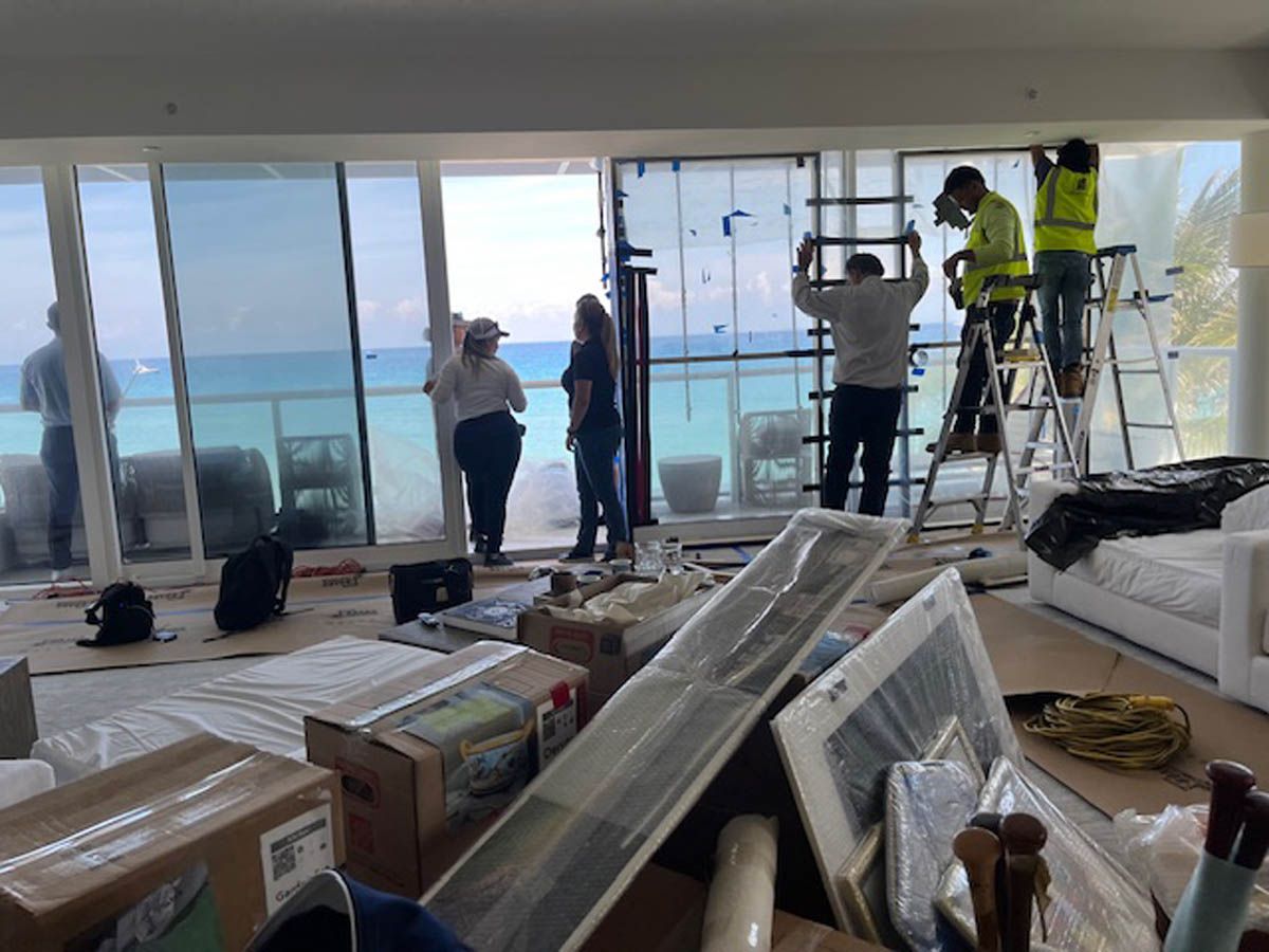 A group of people are working on a large window in a living room.