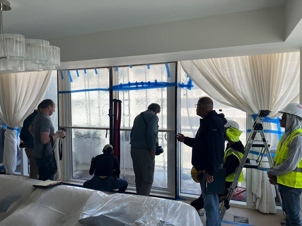 A group of people are standing around a window in a room.