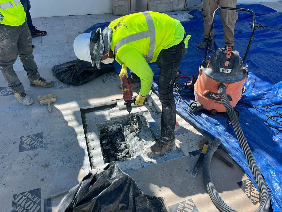 A man is working on a concrete floor with a vacuum cleaner.