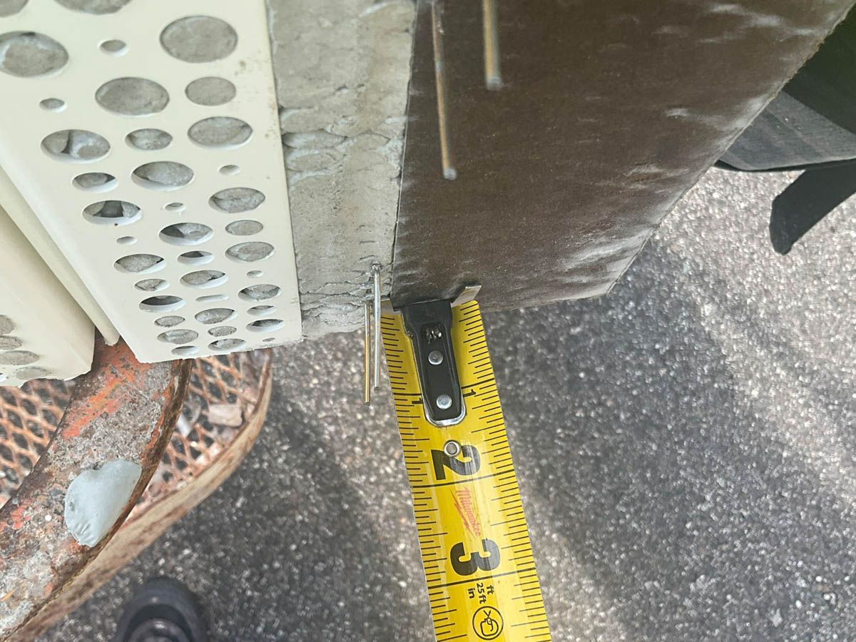 A person is measuring a piece of concrete with a tape measure