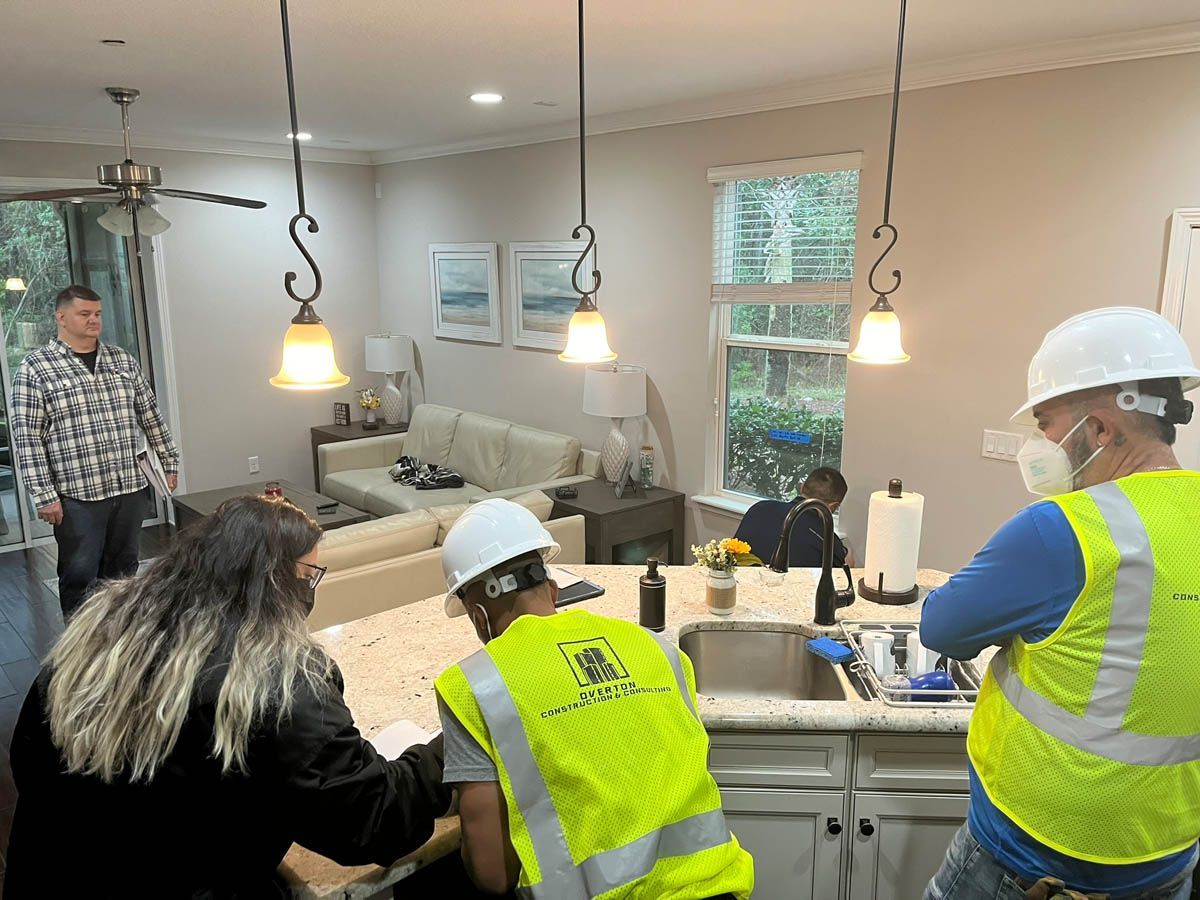 A group of construction workers are working on a kitchen in a house.