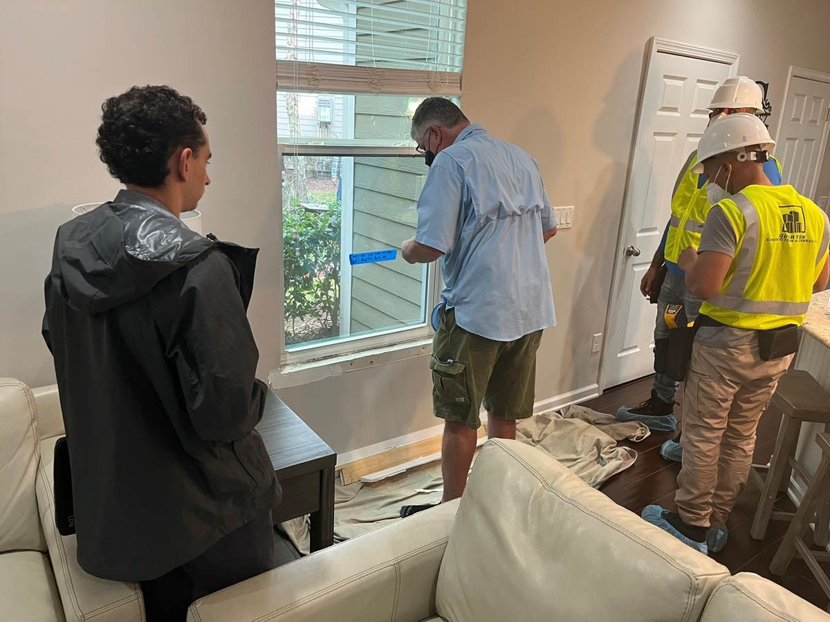 A group of people are working on a window in a living room.