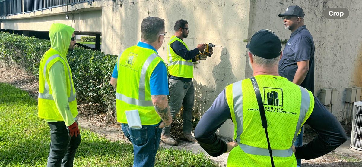 A group of construction workers in yellow vests are working on a wall.