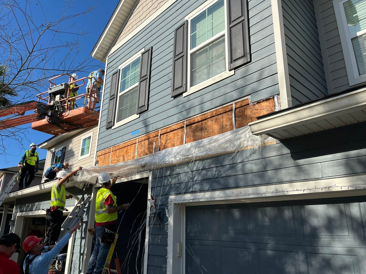 A group of construction workers are working on the side of a house.