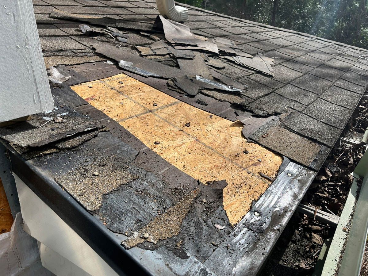 A close up of a roof with shingles missing and a gutter.
