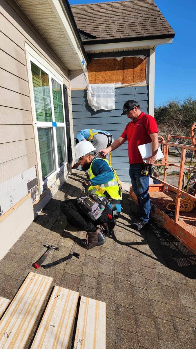 Two construction workers are working on the side of a house.