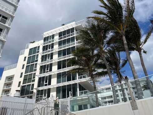 A tall building with a lot of windows and palm trees in front of it.