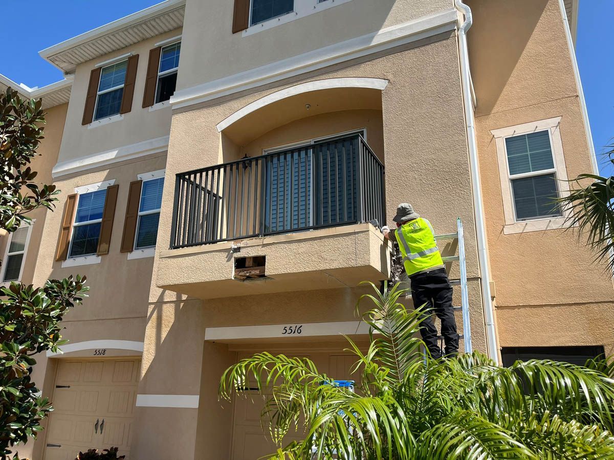 A man is standing on a ladder in front of a building.