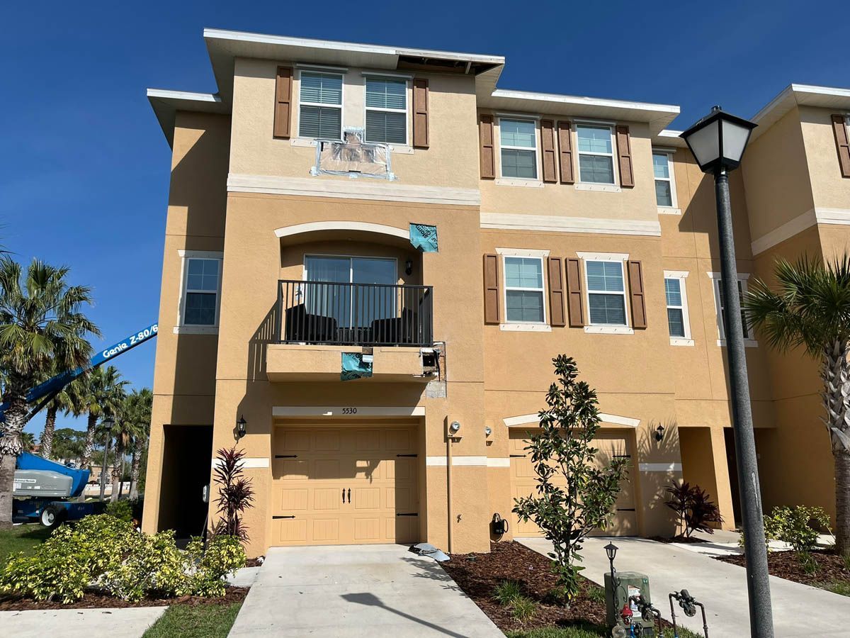 A large house with a balcony and shutters is being painted.