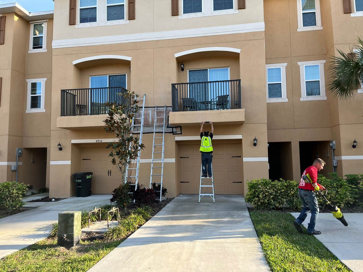 A man is standing on a ladder in front of a building.