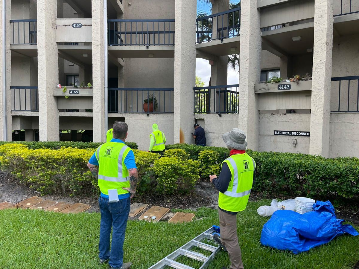A group of men in yellow vests are standing in front of a building.