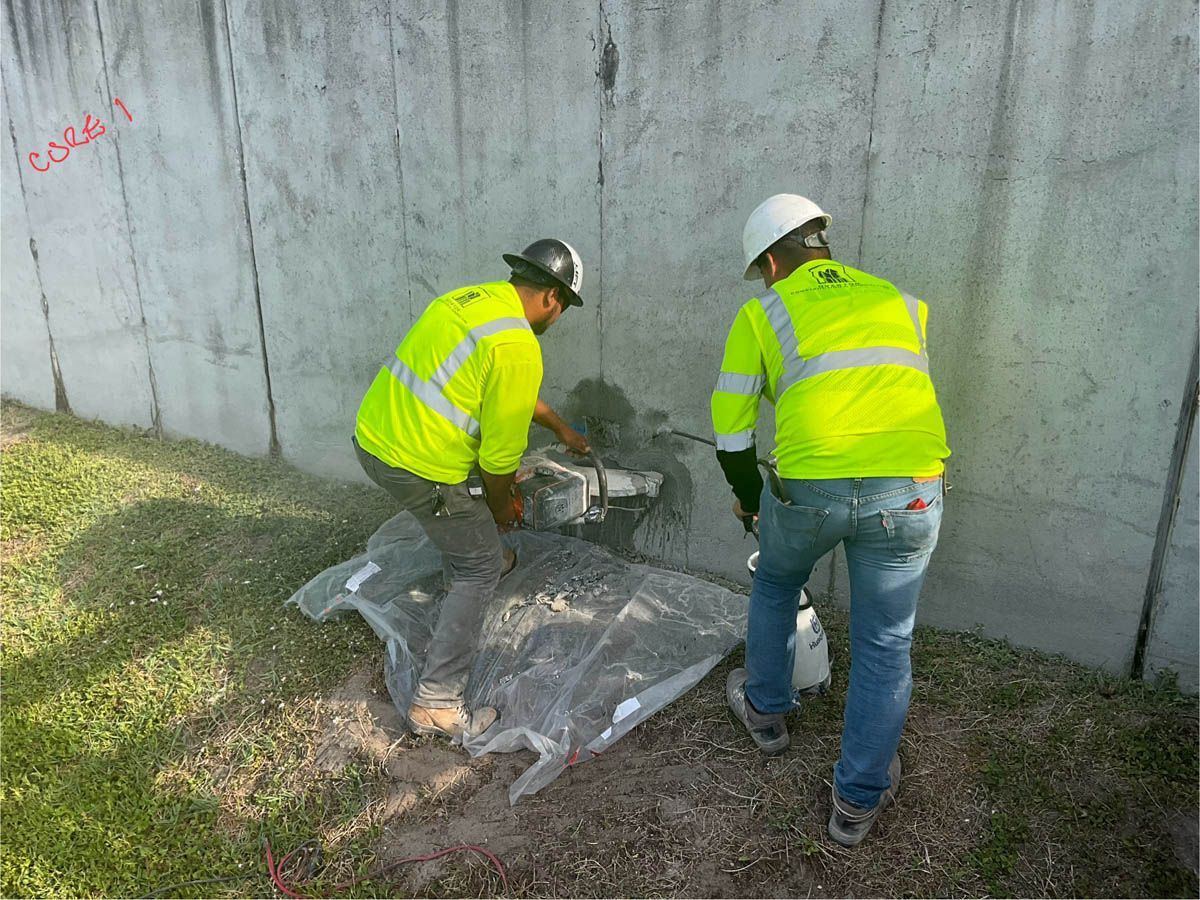 Two construction workers are working on a concrete wall.