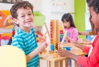 Kindergarten students smile when playing toy in playroom at preschool