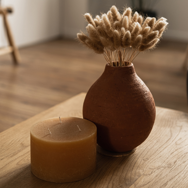 A vase with flowers and a candle on a table