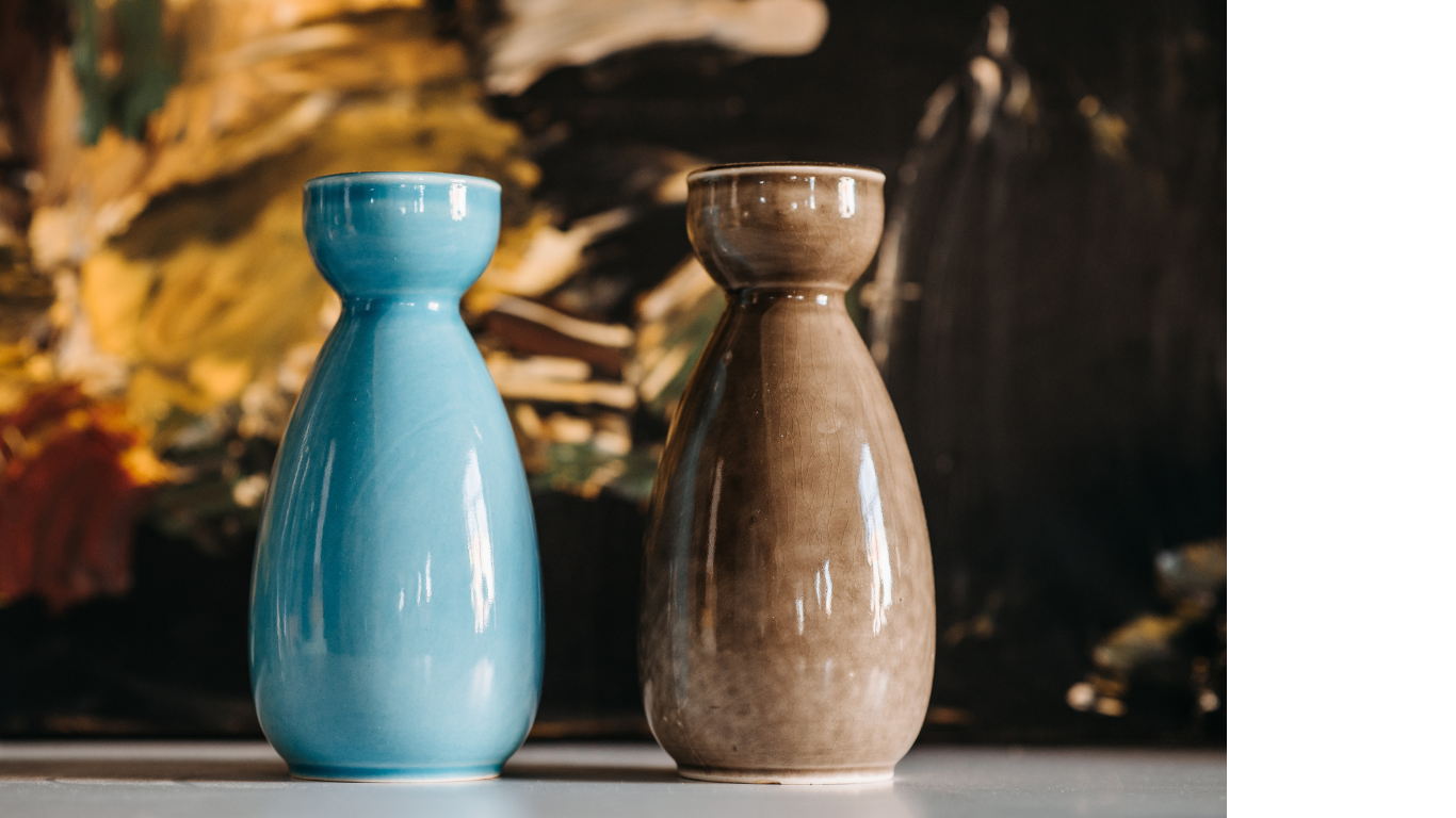 Two vases are sitting on a table in front of a painting.