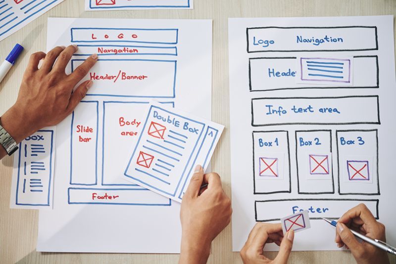 person pointing to a website wireframe on paper