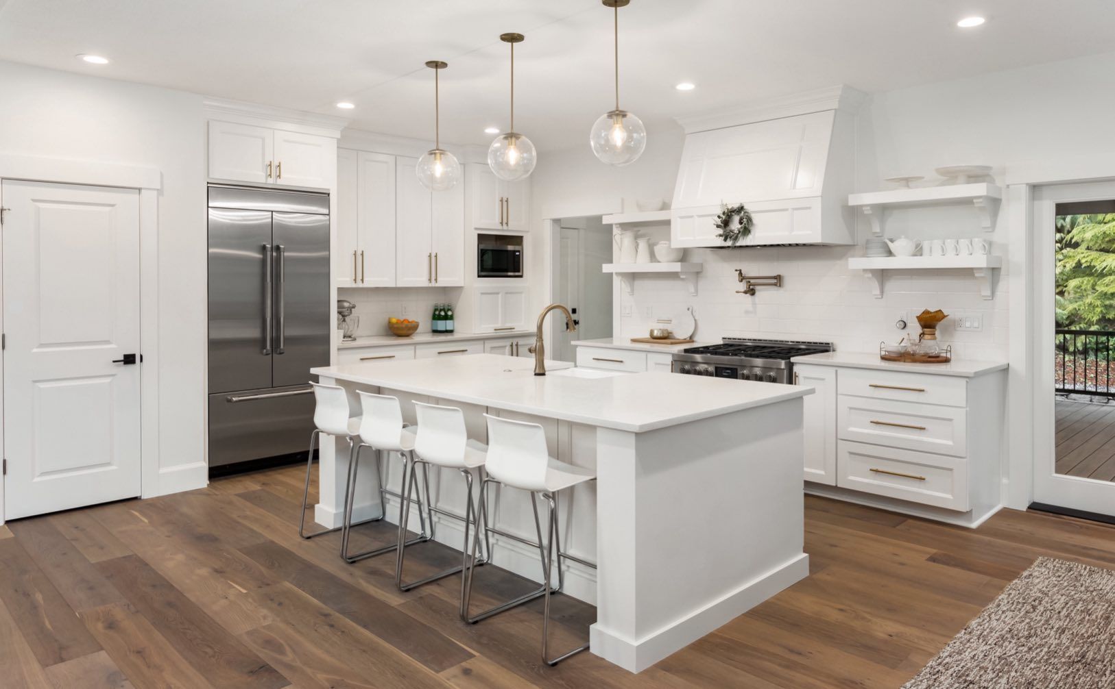 Modern white kitchen with island, stainless steel appliances, and hardwood floors.