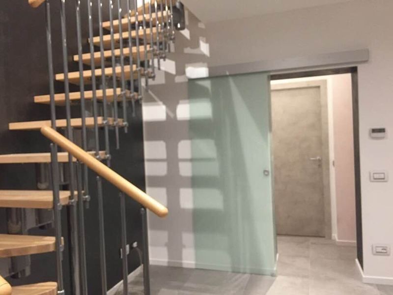 Un corridoio con una scala e una porta scorrevole in vetro