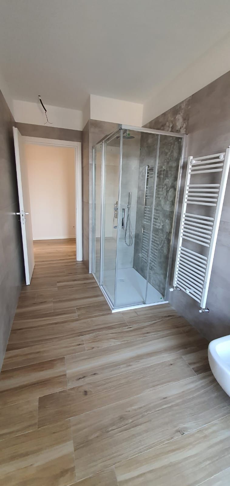 Un bagno con cabina doccia e portasciugamani.