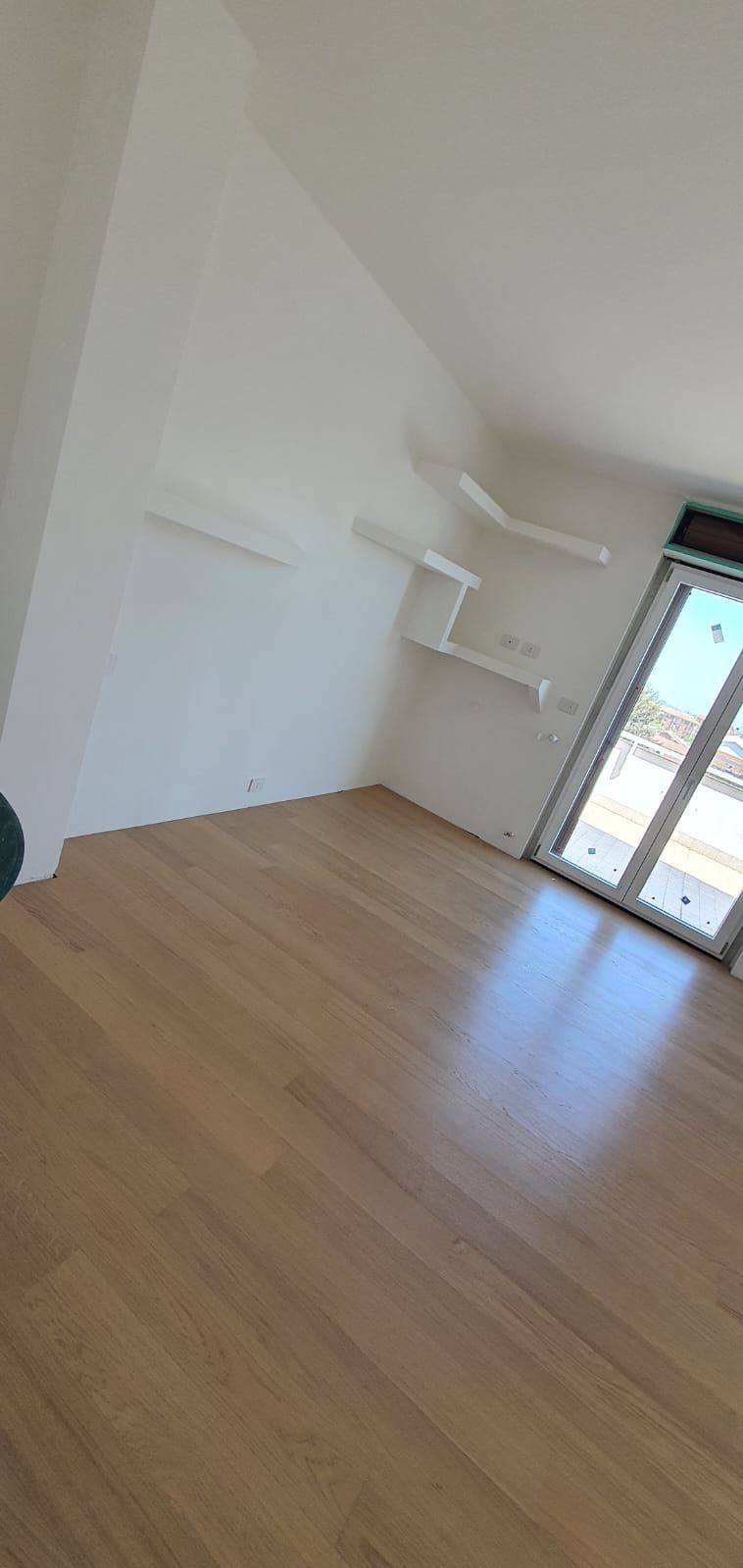 Una stanza vuota con pavimento in legno e pareti bianche.